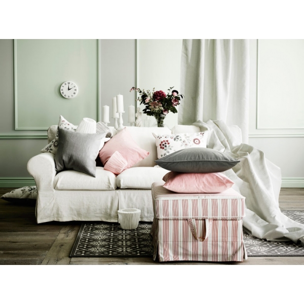 Three-seat sofa filled with cushions, cushion covers and lamp shades in grey, white and pink